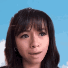 a close up of a woman 's face against a blue sky