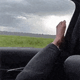 a person is sitting in a car with their feet out the window and looking out the window .