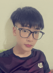 a young boy wearing glasses and a black shirt with a white arrow on the sleeve