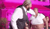 a man in a suit is dancing with a woman in a white crop top .
