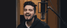 a man with a beard is singing into a microphone and smiling