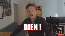 a man in a black shirt with the word rien on his chest