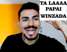 a man with a beard and mustache is smiling and holding a sign that says ta laaaa papai winzada .