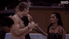 a group of shirtless men are hugging each other in a room .