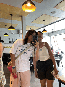 two women are posing for a picture and one has a shirt that says aoay on it