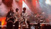 a group of men are playing guitars on a stage with a drum set that says dirty dog