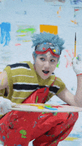 a young man with blue hair is kneeling down holding a brush