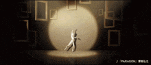a person dancing in front of a spotlight with the word paragon below them