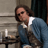 a man in a blue jacket smoking a cigarette next to a candle