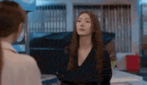 a woman with long hair is standing next to another woman in a room and looking at the camera .