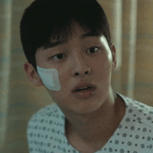 a young man in a hospital gown has a bandage on his forehead