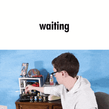 a man sitting at a desk with the word waiting on the bottom