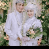 a bride and groom are posing for a picture . the bride is wearing a hijab .