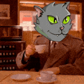 a man is sitting at a table with a cat on his head holding a cup of coffee