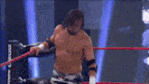 a wrestler without a shirt is standing in a wrestling ring