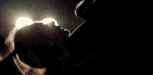 a man and woman are kissing in the dark in front of a car headlight .