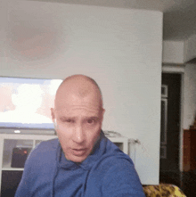 a man in a blue shirt takes a selfie in front of a tv