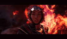 a woman wearing a futuristic helmet is standing in front of a fire