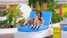 a woman in a bikini sits on a blue lounge chair with the words " what did you guys do " on the bottom right