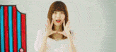 a young woman is making a heart with her hands in front of her face .