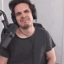 a man wearing headphones and a microphone is making a face .