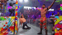 a wrestler is standing in a ring with his arms in the air .