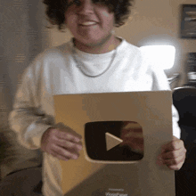 a young man in a white shirt is holding a gold plaque that says ' sponsored by vickypaper ' on it