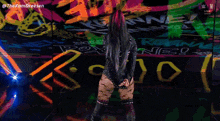 a woman in a black bodysuit stands in front of a wall that has the word reign on it