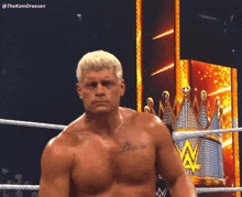 a shirtless wrestler with a tattoo on his chest stands in a ring