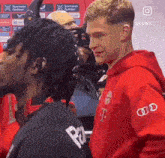 a man in a red t-mobile hoodie stands next to another man in a black shirt
