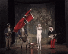 a man in a white suit is holding a red flag on a stage