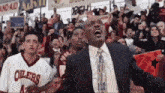 a man in a suit and tie is standing in front of a crowd of people in a stadium .