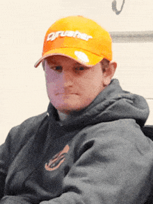 a man wearing an orange hat that says crusher on it