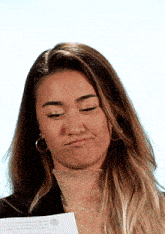 a woman making a funny face while holding a piece of paper with the word mexico on it