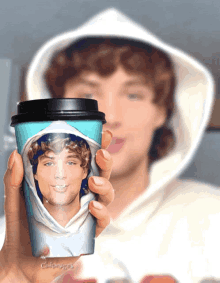a person is holding a cup that has a picture of a man on it