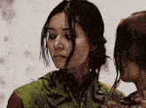 two women are standing next to each other and one is wearing a green jacket