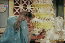 a woman in a blue dress is kneeling down in front of a statue with ultra written on the bottom