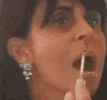 a woman wearing a necklace and earrings is taking a picture of herself in a mirror .