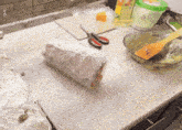 a plastic bag of food sits on a counter next to a cutting board and scissors