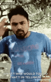 a man with a beard is wearing a blue shirt and talking to someone .