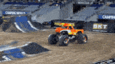 a monster truck is driving on a dirt track in front of a bkt sign