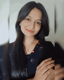 a woman wearing a black shirt with red buttons on the front smiles for the camera