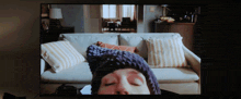 a person wearing a knitted hat is laying on a couch with their eyes closed