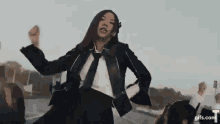 a woman in a suit and tie is dancing in front of a group of people .