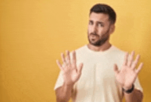 a man with a beard is making a stop gesture with his hands .