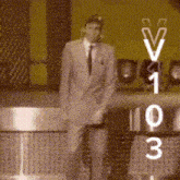 a man in a suit and tie stands in front of a scoreboard with the numbers 1 through 3