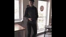 a young man standing in front of a window holding a cell phone