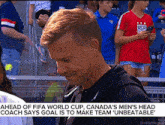 a man stands in front of a crowd with a caption that says ahead of fifa world cup canada 's men 's head coach