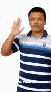 a man in a blue and white striped shirt is waving his hand