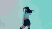 a woman in a white top and black shorts is dancing .